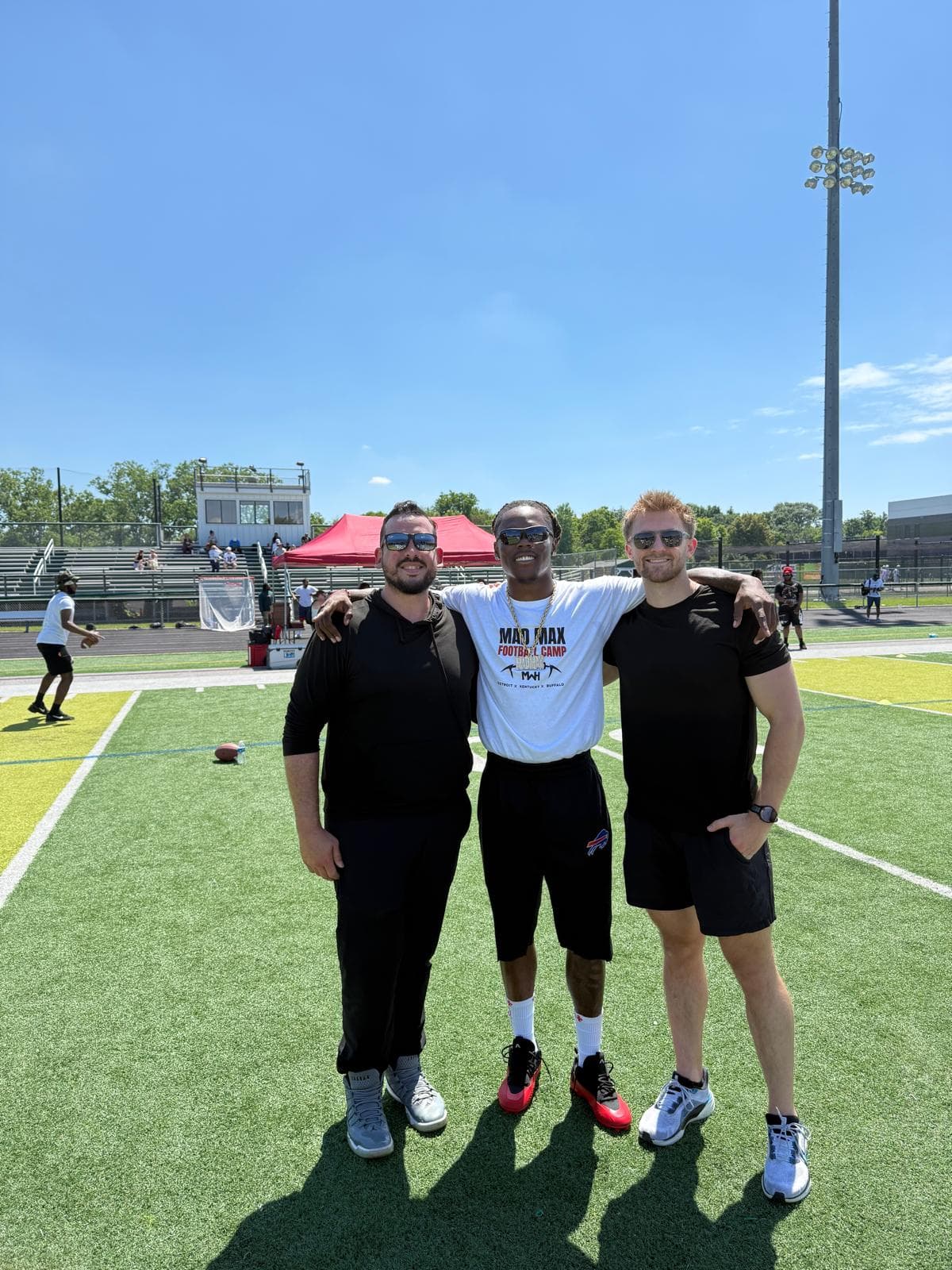 Phyx Performance coaches with an athlete on a football field